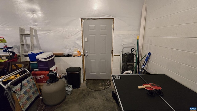 recreation room featuring unfinished concrete floors and concrete block wall