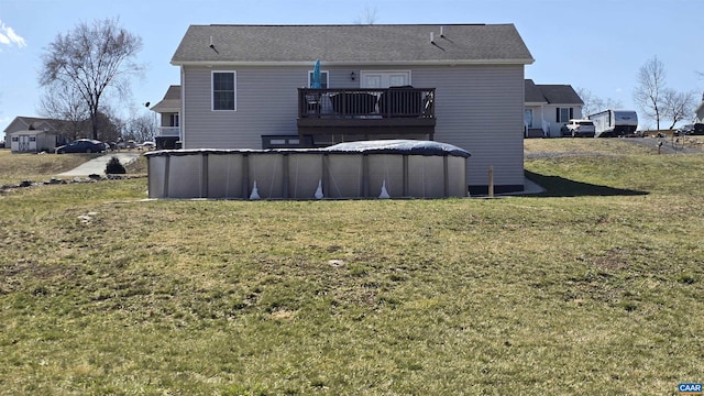 back of property featuring a deck, a lawn, and an outdoor pool