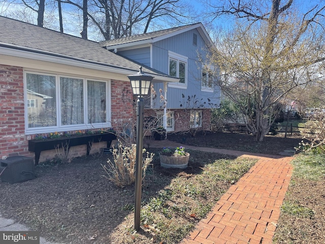 view of home's exterior featuring brick siding and roof with shingles