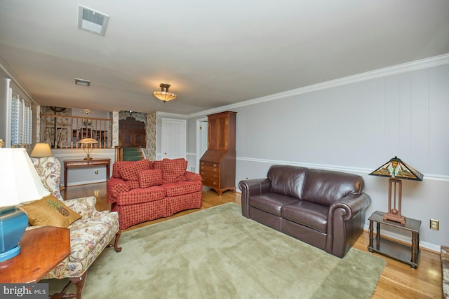 living area featuring visible vents, wood finished floors, and ornamental molding