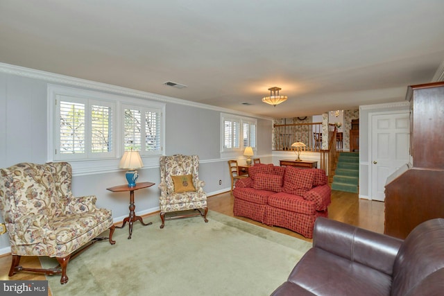 living area with visible vents, ornamental molding, wood finished floors, stairway, and baseboards