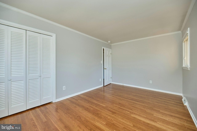 unfurnished bedroom with a closet, baseboards, light wood finished floors, and ornamental molding