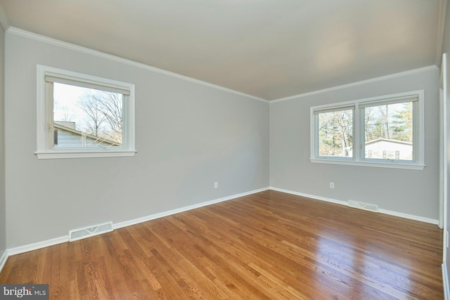 unfurnished room with crown molding, wood finished floors, visible vents, and baseboards