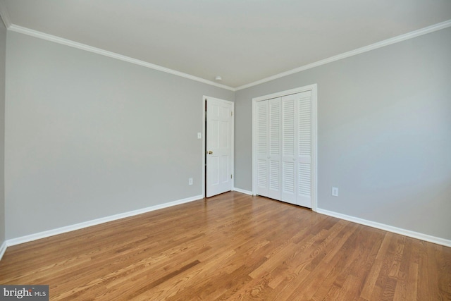 unfurnished bedroom with a closet, baseboards, crown molding, and light wood finished floors