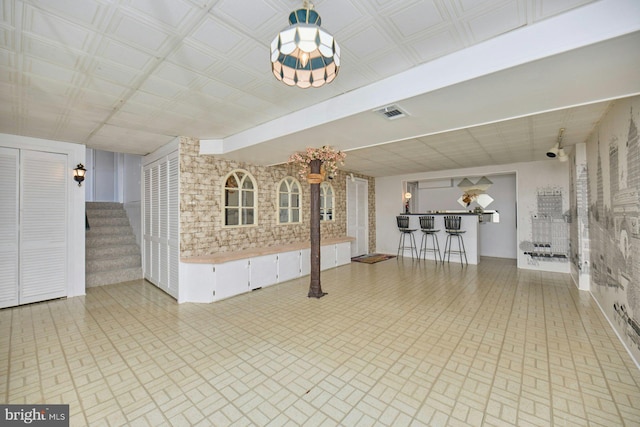 unfurnished living room featuring a bar, stairway, and visible vents