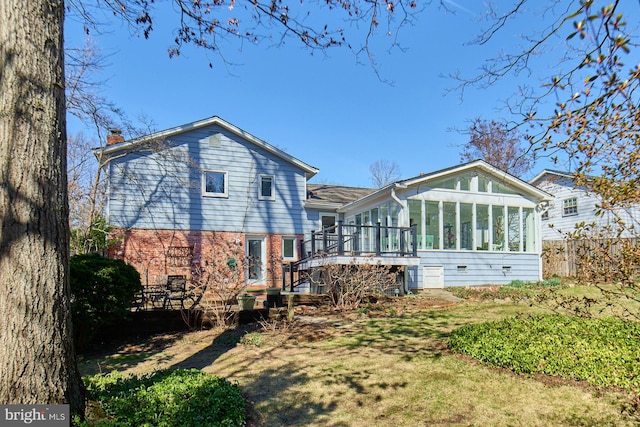 rear view of house with fence, a sunroom, a wooden deck, brick siding, and a chimney