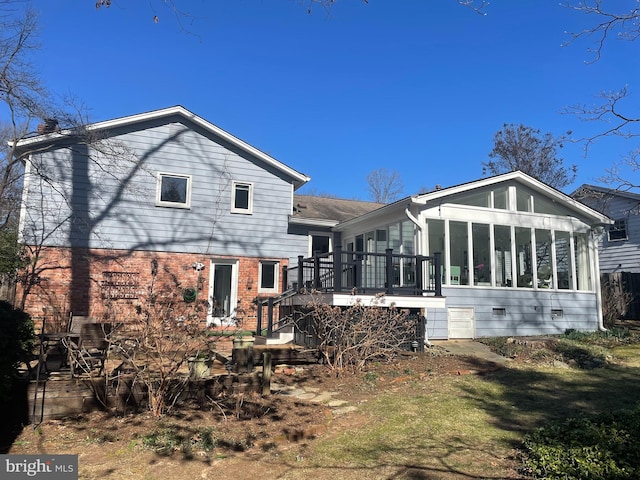 rear view of property with stairs, a deck, brick siding, and a sunroom