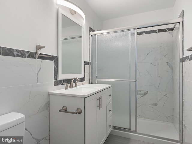 full bathroom featuring vanity, a shower stall, toilet, and tile walls