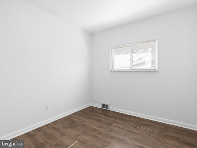 unfurnished room with visible vents, baseboards, and dark wood-style floors