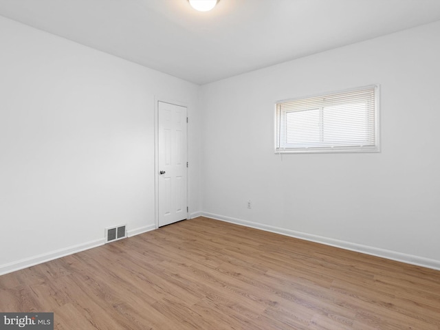 spare room featuring light wood-style flooring, baseboards, and visible vents