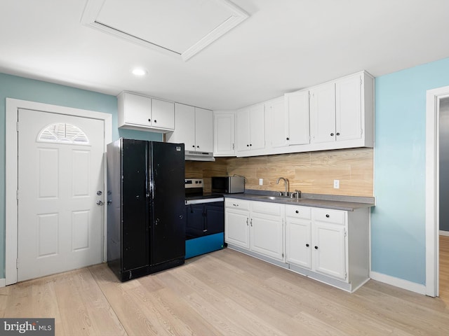 kitchen with freestanding refrigerator, a sink, range with electric cooktop, white cabinets, and stainless steel microwave