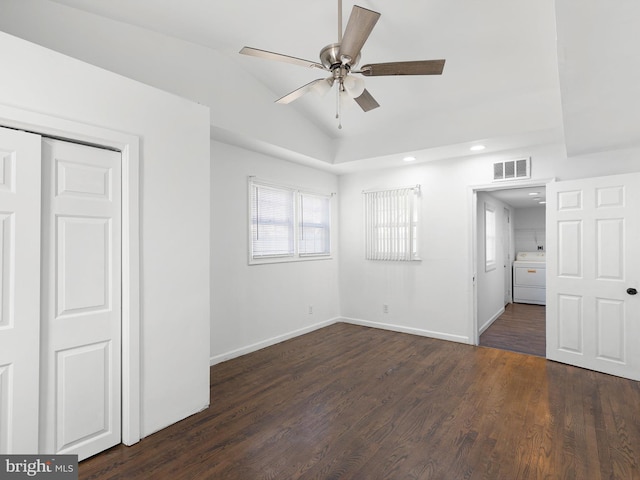 unfurnished bedroom featuring visible vents, lofted ceiling, baseboards, washer / dryer, and dark wood-style flooring