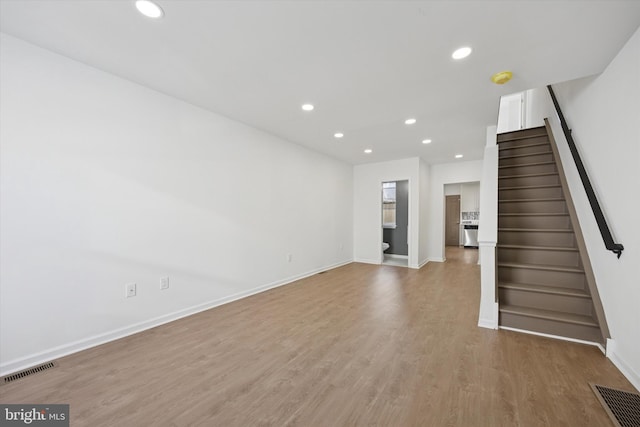 unfurnished living room with baseboards, visible vents, recessed lighting, stairs, and light wood-type flooring