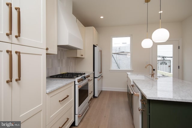 kitchen with white appliances, light stone countertops, an island with sink, custom range hood, and backsplash