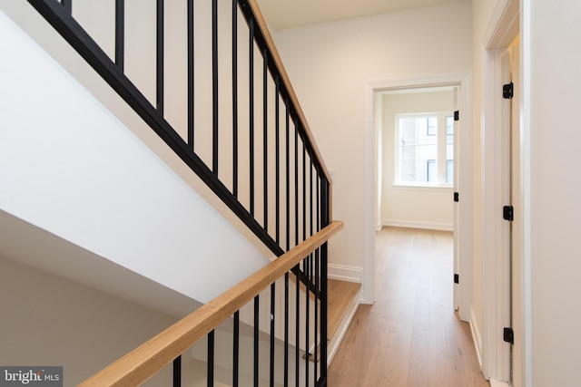 corridor featuring stairs, baseboards, and light wood finished floors