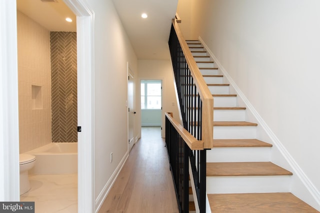 stairway featuring wood finished floors, recessed lighting, and baseboards