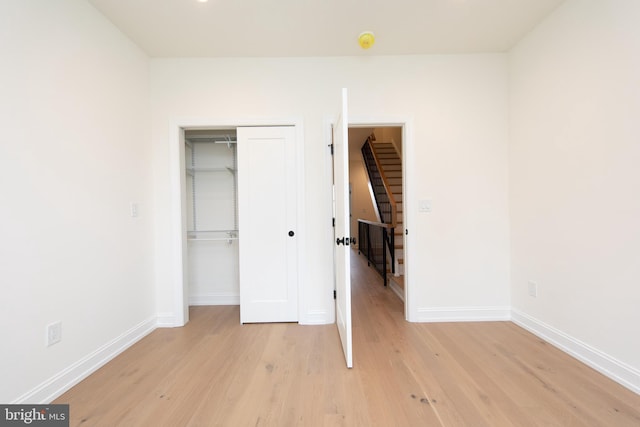 unfurnished bedroom with a closet, baseboards, and light wood finished floors