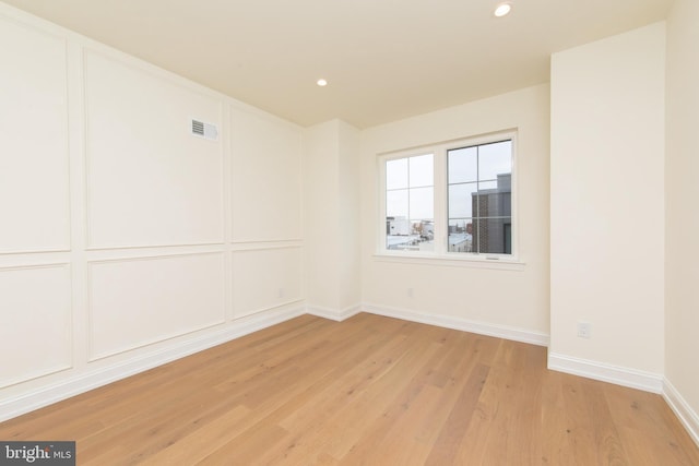 empty room with light wood finished floors, visible vents, baseboards, recessed lighting, and a decorative wall