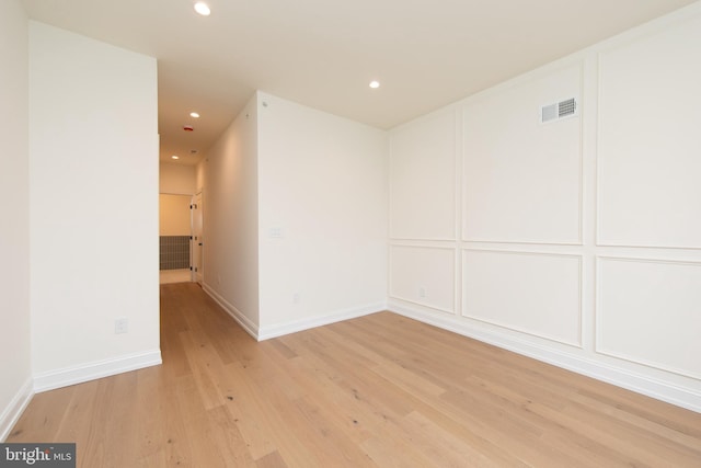 empty room with recessed lighting, visible vents, light wood-style flooring, and a decorative wall