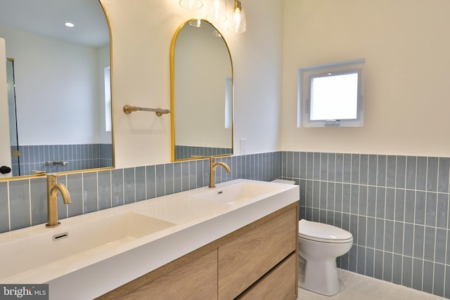 bathroom featuring double vanity, toilet, wainscoting, and a sink