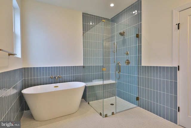 full bath with tile walls, a freestanding tub, a wainscoted wall, and tiled shower