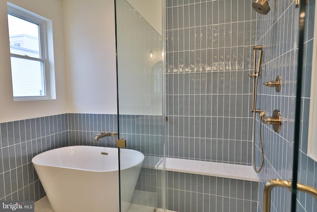 full bath with a tile shower, tile walls, and a freestanding tub