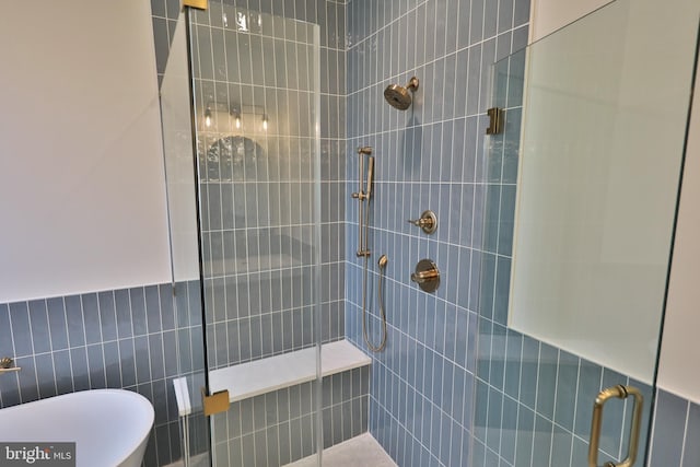 full bathroom with a soaking tub, a stall shower, and tile walls