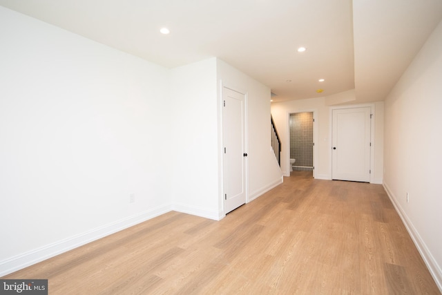 unfurnished room featuring recessed lighting, stairway, baseboards, and light wood-style floors