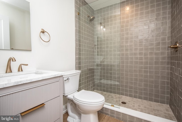 bathroom featuring vanity, toilet, and tiled shower