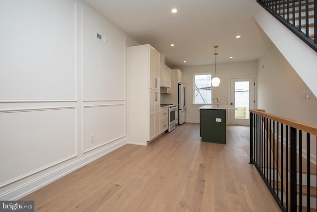 kitchen with visible vents, freestanding refrigerator, light wood-style floors, high end white range, and white cabinetry