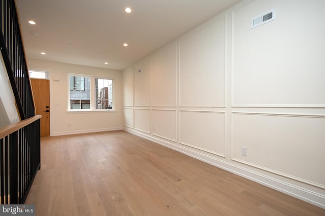 unfurnished room featuring a decorative wall, recessed lighting, light wood-style floors, and visible vents