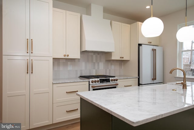 kitchen featuring pendant lighting, custom range hood, a sink, decorative backsplash, and high end appliances