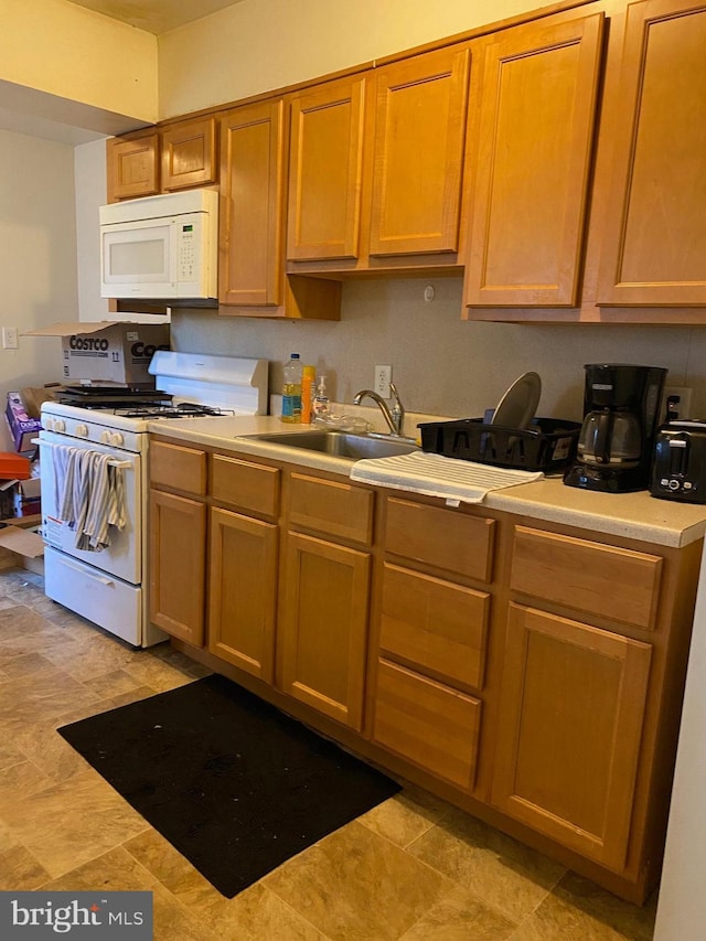 kitchen featuring white appliances, light countertops, and a sink