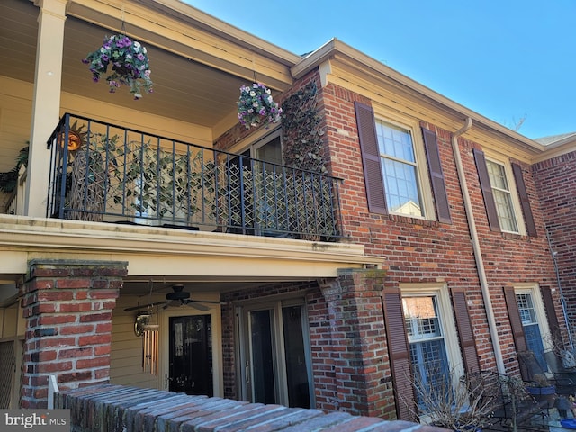 view of property exterior with a balcony, brick siding, and ceiling fan