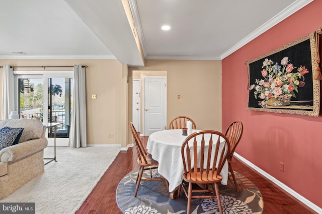 dining room featuring wood finished floors, baseboards, and ornamental molding