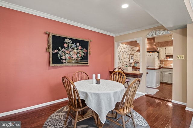 dining room featuring dark wood finished floors, crown molding, and baseboards