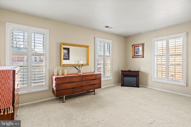 sitting room featuring a glass covered fireplace, carpet, visible vents, and baseboards