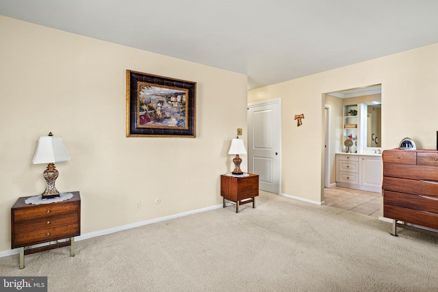 bedroom with baseboards, light carpet, and ensuite bath