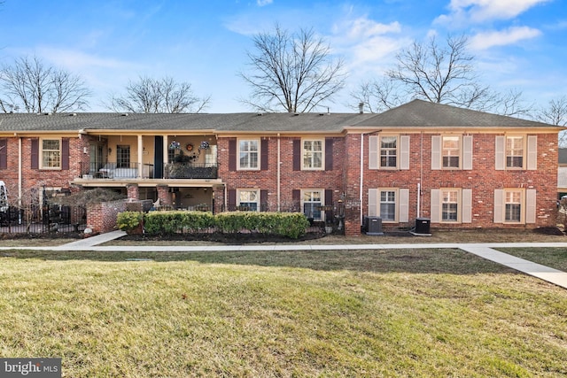 view of front facade featuring cooling unit, brick siding, a front lawn, and fence