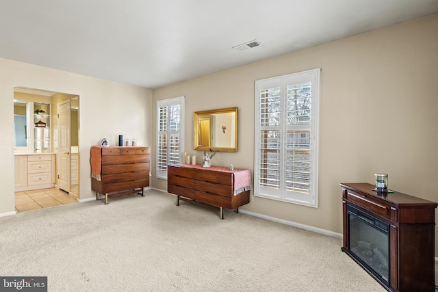 living area with carpet flooring, baseboards, visible vents, and a glass covered fireplace