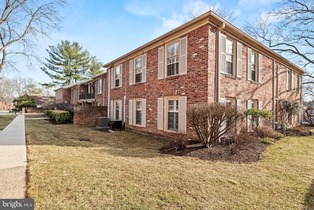 view of side of home with central air condition unit, brick siding, and a lawn