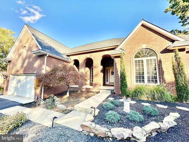 view of front of property with aphalt driveway, a garage, brick siding, and roof with shingles