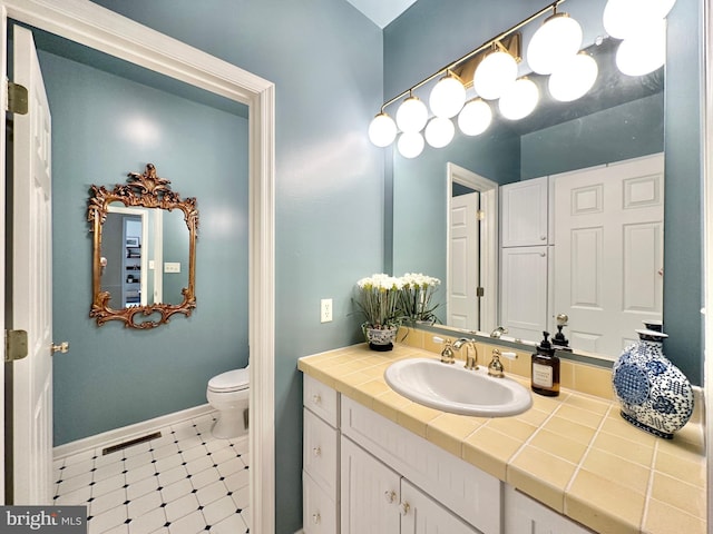 bathroom with baseboards, toilet, and vanity