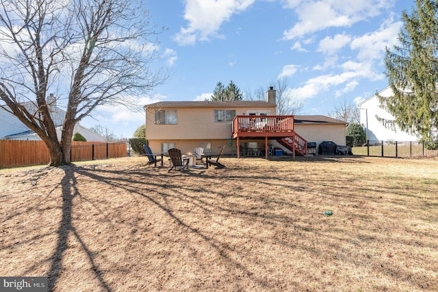 rear view of house featuring fence, stairway, a wooden deck, a chimney, and a yard