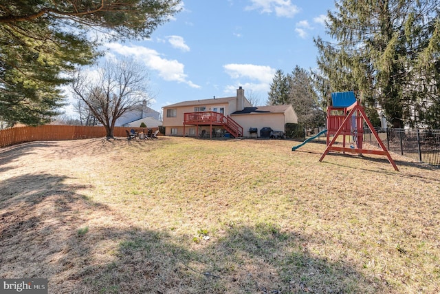 view of yard with stairway, fence, a wooden deck, and a playground