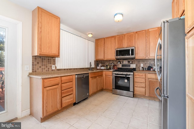 kitchen featuring backsplash, light brown cabinetry, light countertops, stainless steel appliances, and a sink