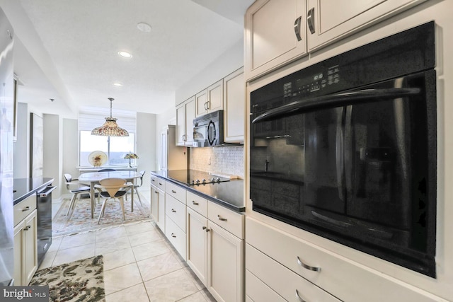 kitchen featuring dark countertops, backsplash, light tile patterned flooring, hanging light fixtures, and black appliances