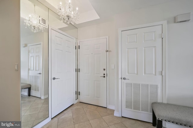 hallway with light tile patterned floors, visible vents, baseboards, and an inviting chandelier