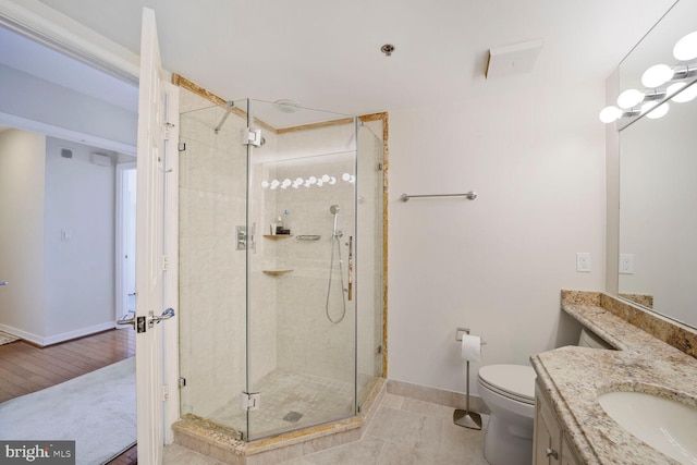 bathroom with baseboards, vanity, a shower stall, and toilet