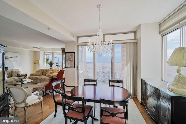 dining area with a wealth of natural light, visible vents, a chandelier, and wood finished floors